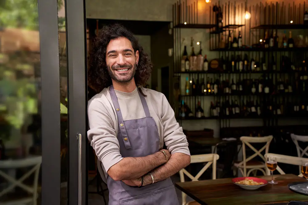 A man in an apron posing in a restaurant